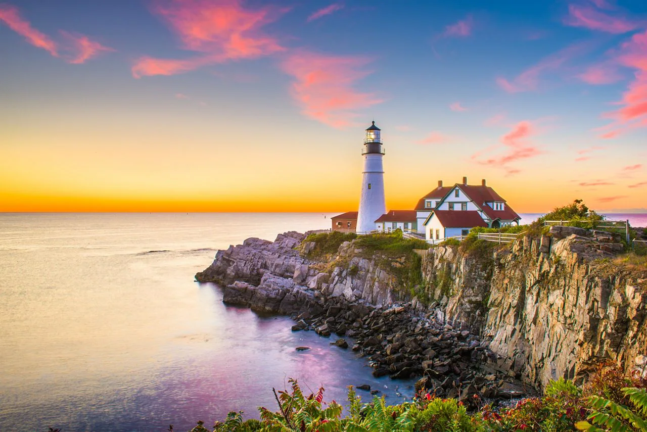 New England lighthouse on a coastal cliff at sunset